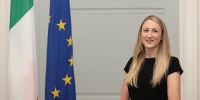 Consul General Anne-Marie Flynn's headshot beside the Irish and European flag