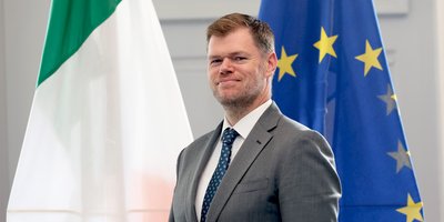 Headshot of David Murphy standing in front of the Irish and EU flags.