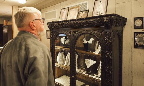 A man admires Irish lace in a wooden cabinet