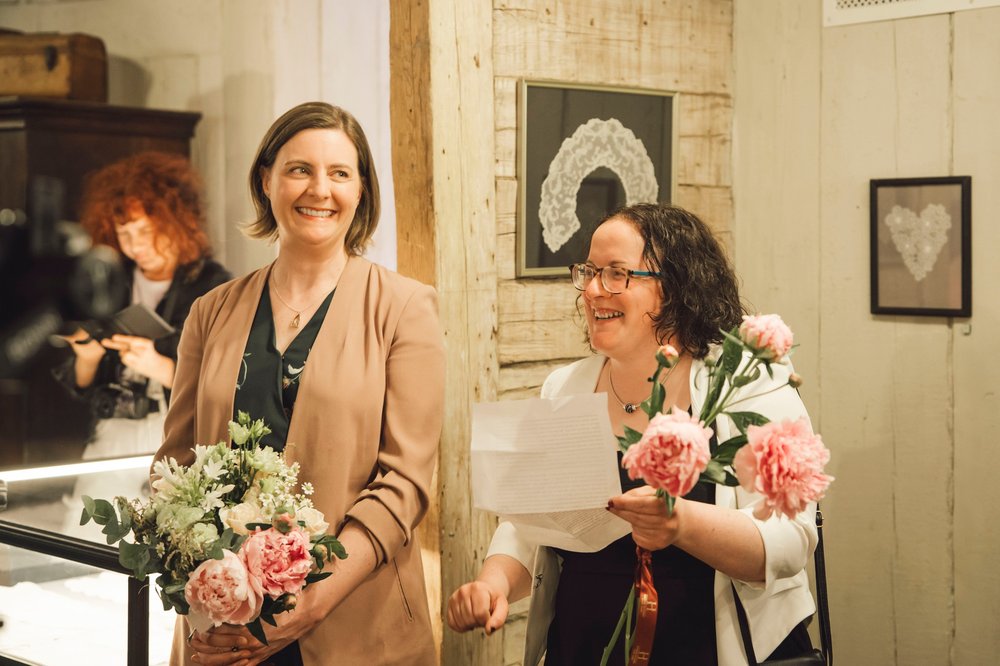 Two women holding bunches of pastel flowers