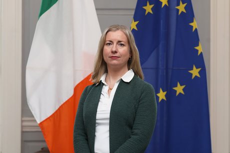 Woman standing in front of Irish and European flags