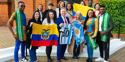 A group photo of Fellows students with the Minister, holding Latin American flags