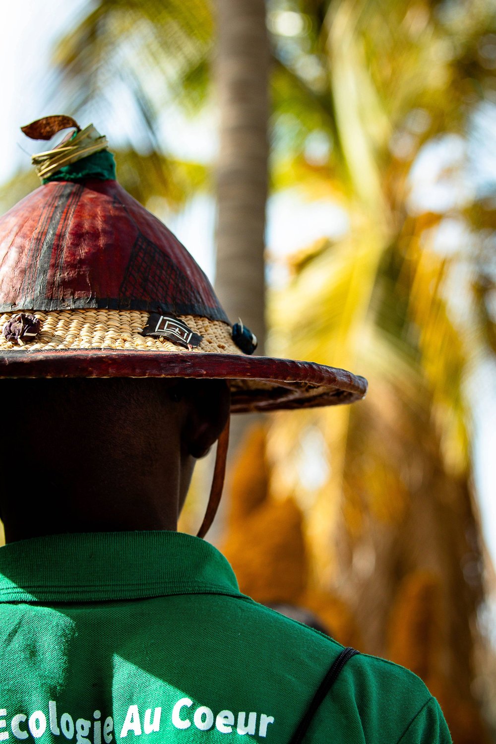 The back of a hat on a person wearing a green tshirt.