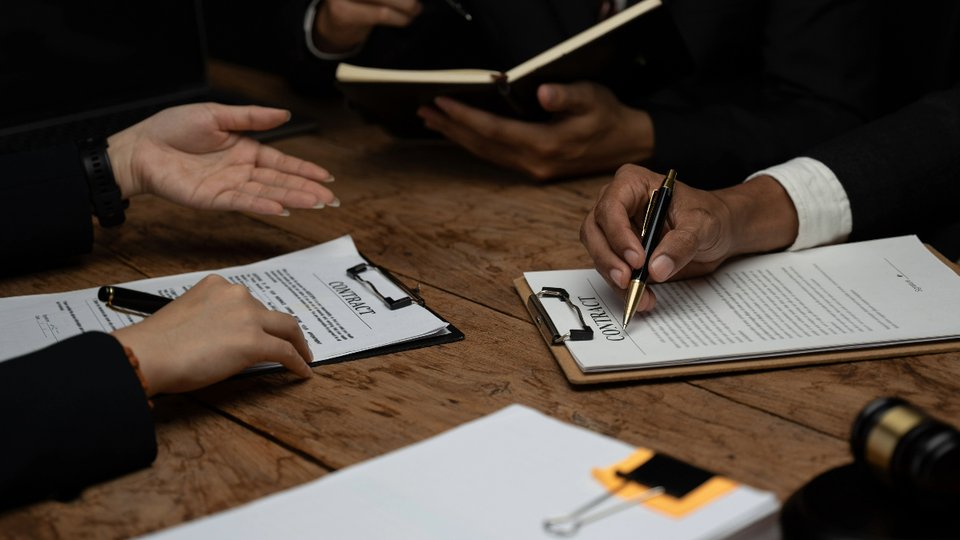 hands writing on contracts on clipboards leaning on table