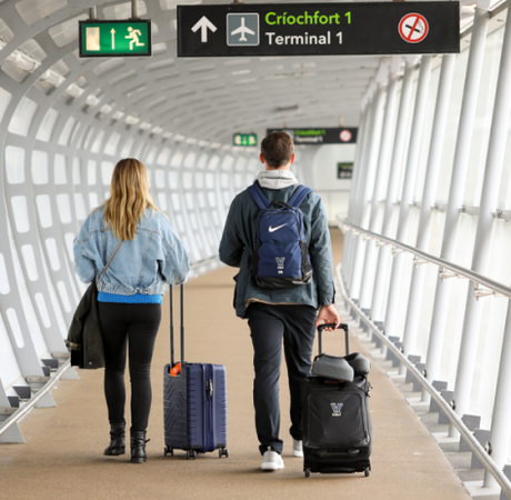 Two people walking through the airport with suitcases.
