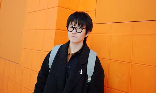 Headshot of literary creator Wuya Li standing against an orange wall