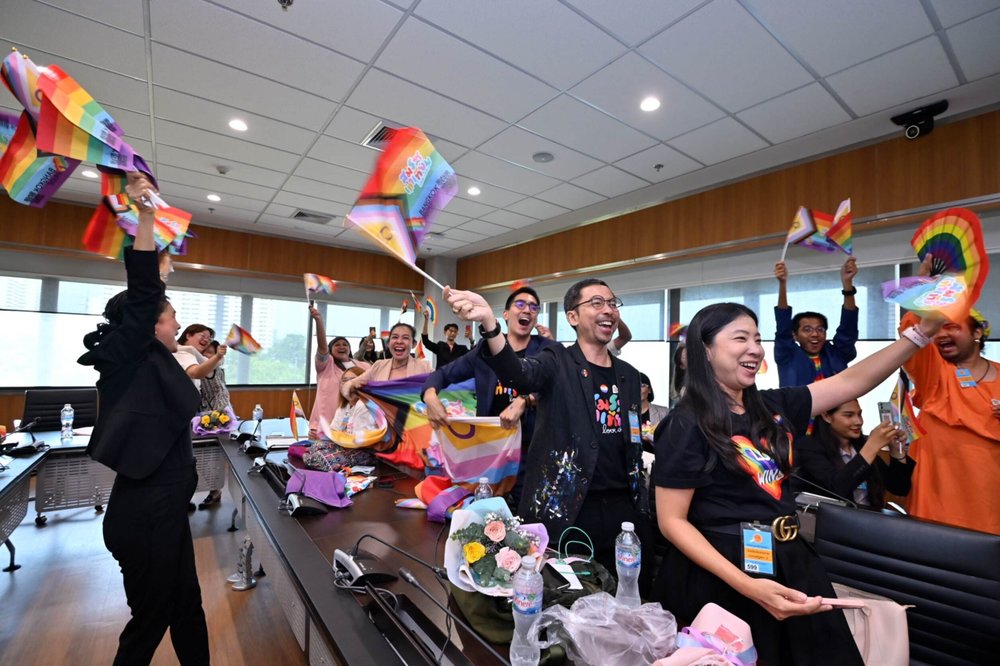 A group of senators celebrating and waving pride flags