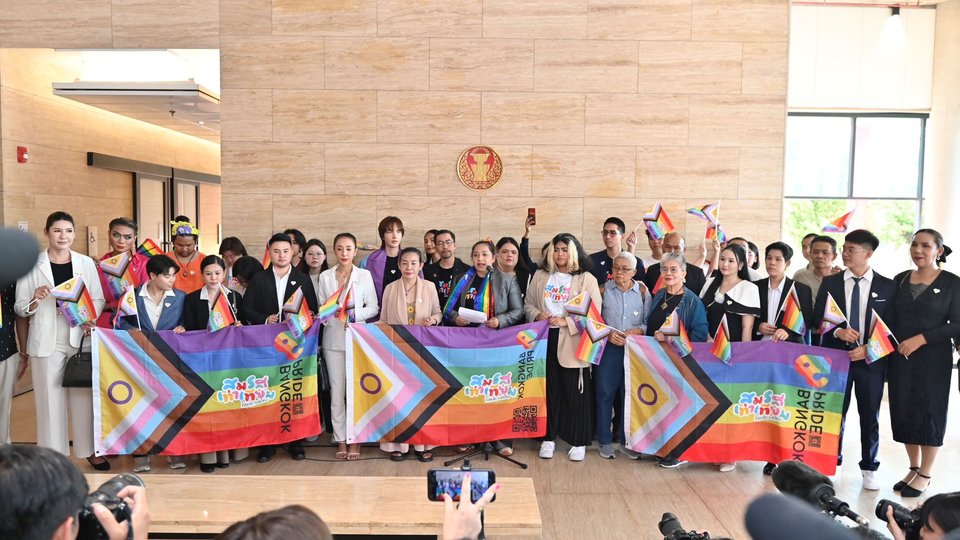 A group of people carrying LGBTQ+ flags