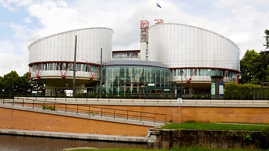 european court building made of two round silver shapes joined in the middle