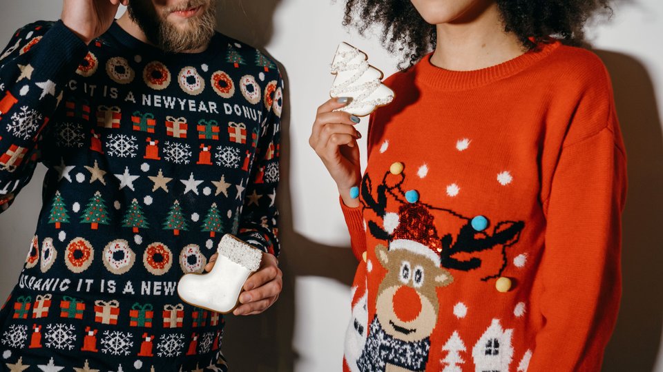 Man and a woman wearing Christmas jumpers