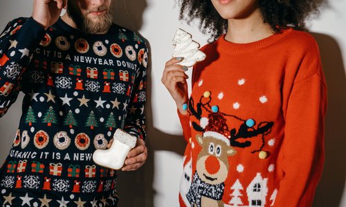 Man and a woman wearing Christmas jumpers
