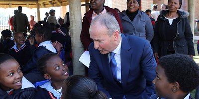 man in suit surrounded by school kids in uniform
