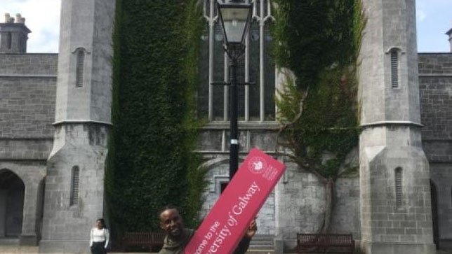 man holding an NUIG sign