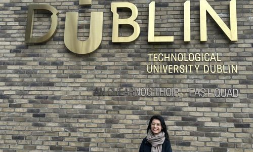 woman standing under TUDublin sign