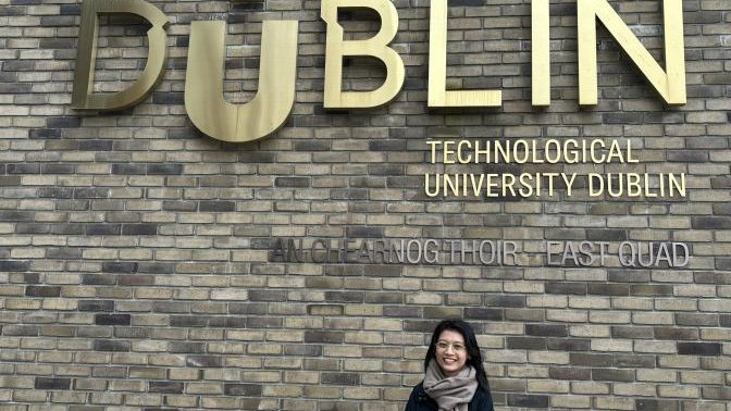 woman standing under TUDublin sign