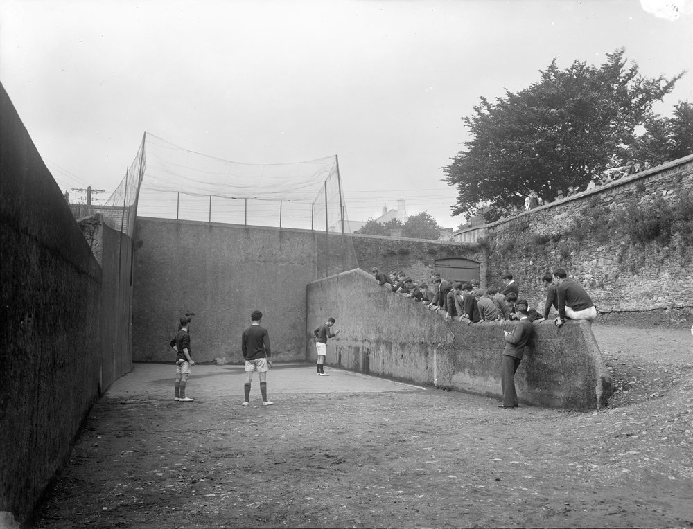 Old photograph of a handball court with people eagerly watching the game along the side