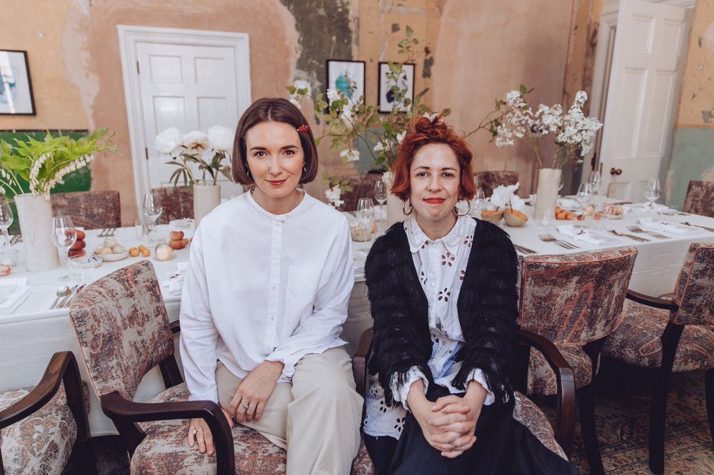 Terri Chandler and Katie Smyth, founders of Worm, sitting in a dining room decorated with wild blooms they have designed